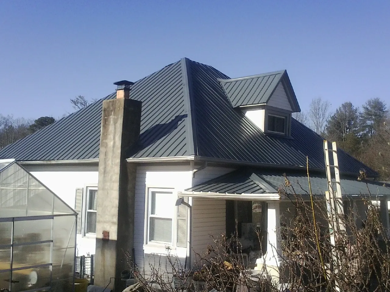 Dark blue standing seam metal roof on a white farmhouse with dormer — Slate & Tile Roof Repair by Roofing Brothers in Hagerman