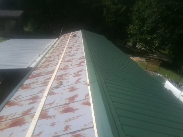 Old rusted panels beside newly installed green metal roofing — Wind Damage Roof Repair by Roofing Brothers in Hagerman