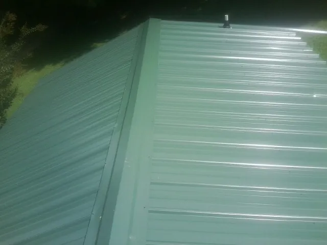 New green metal panels meeting at the ridge of a roof — Flat Roof Repair work by our crew in Hagerman