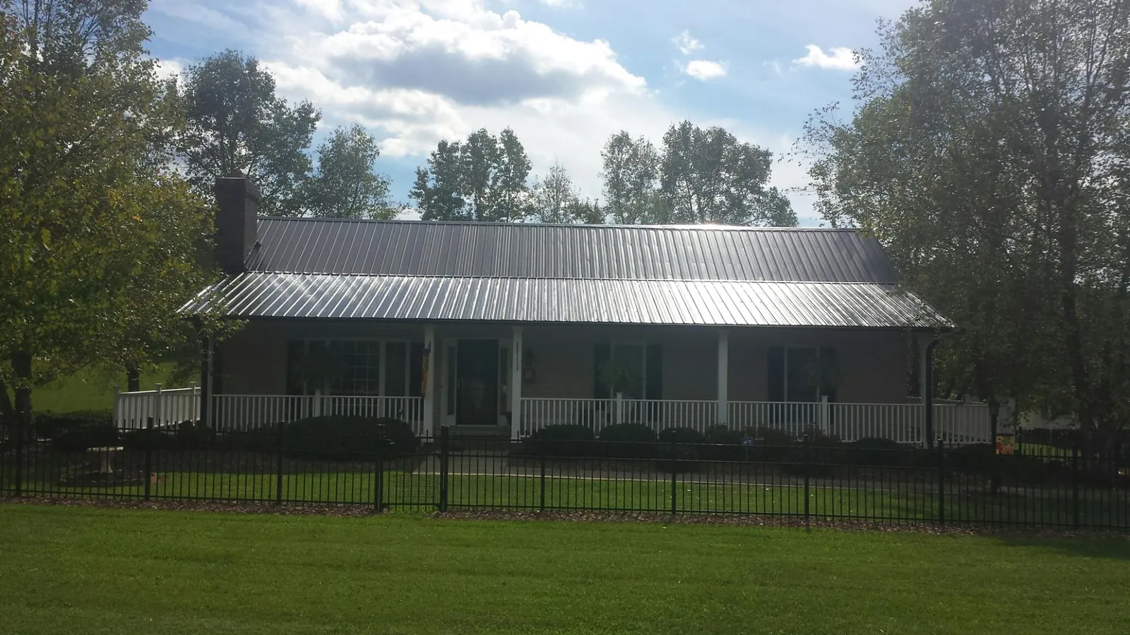 Gray metal roof on a brick ranch with a full width front porch — Gutter Guard Installation work by our crew in Hagerman