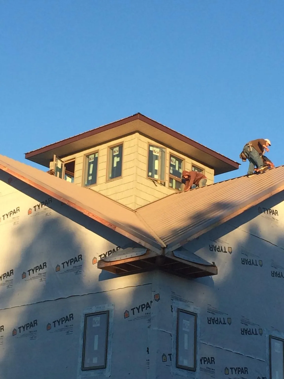Roofers working around a rooftop cupola on a new metal roof at sunset — Roof Waterproofing in Hagerman by Roofing Brothers